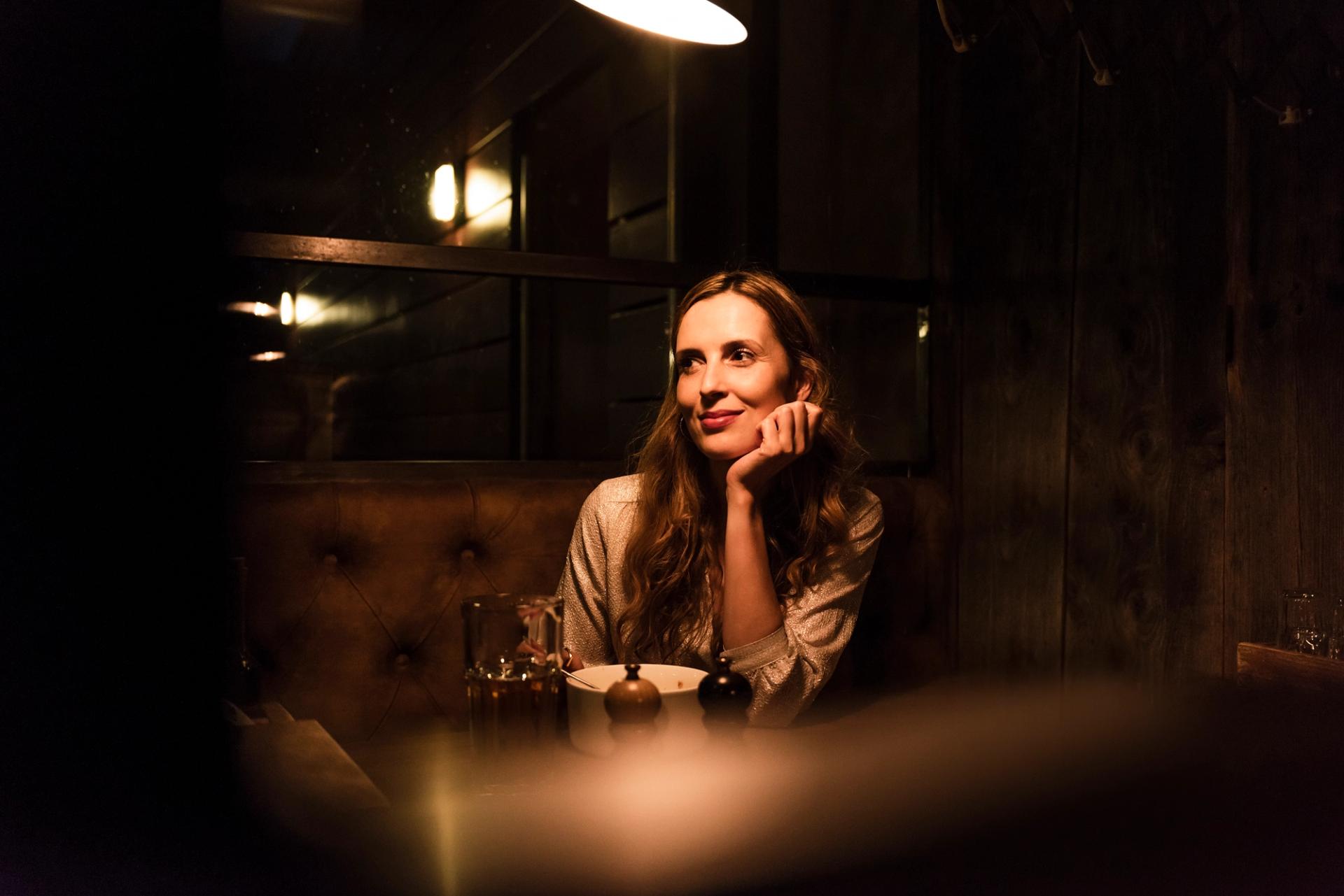 A woman sitting alone at a table in a restaurant.