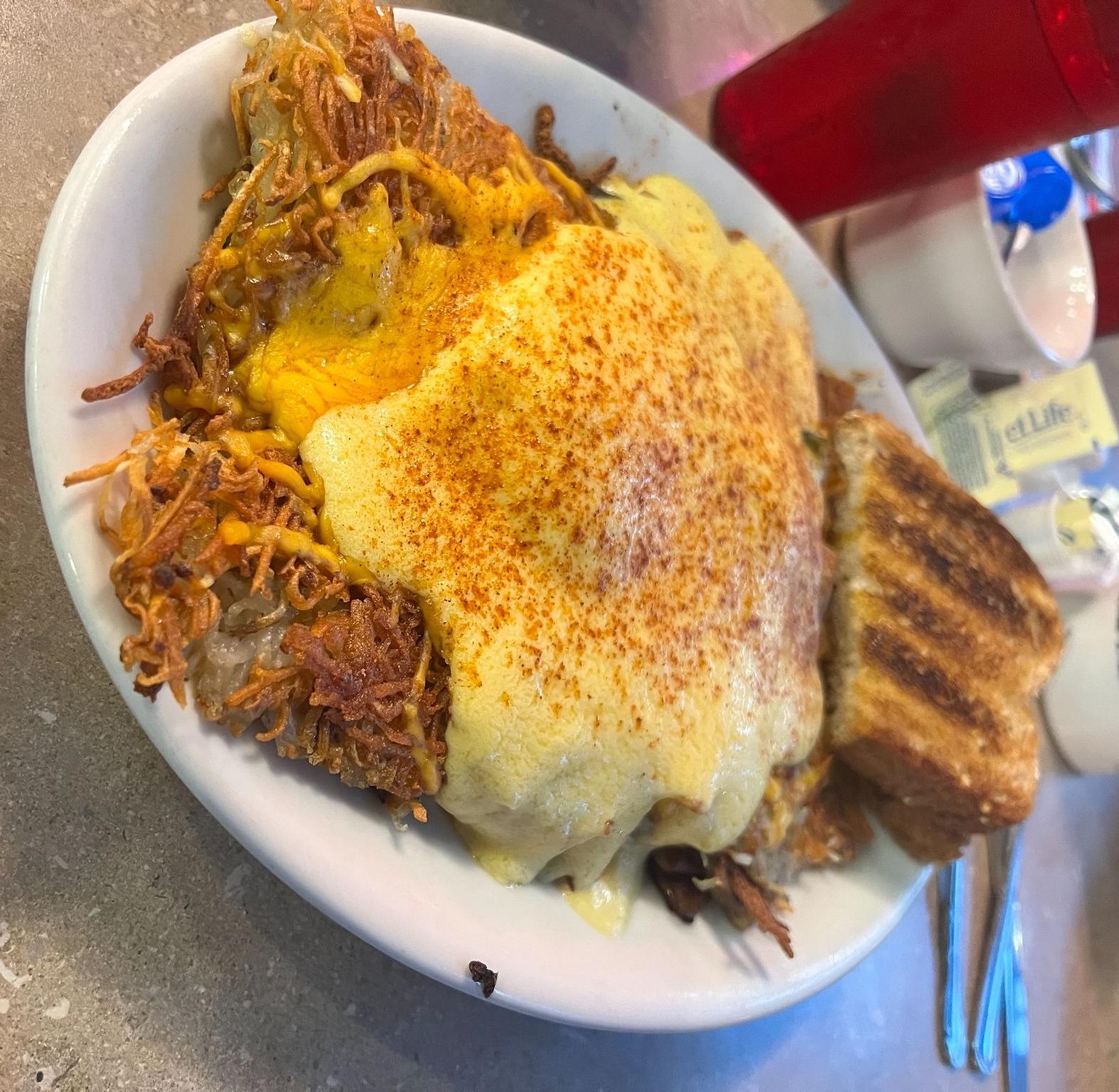 A plate with hashbrowns, toast eggs and hollandaise sauce with paprika