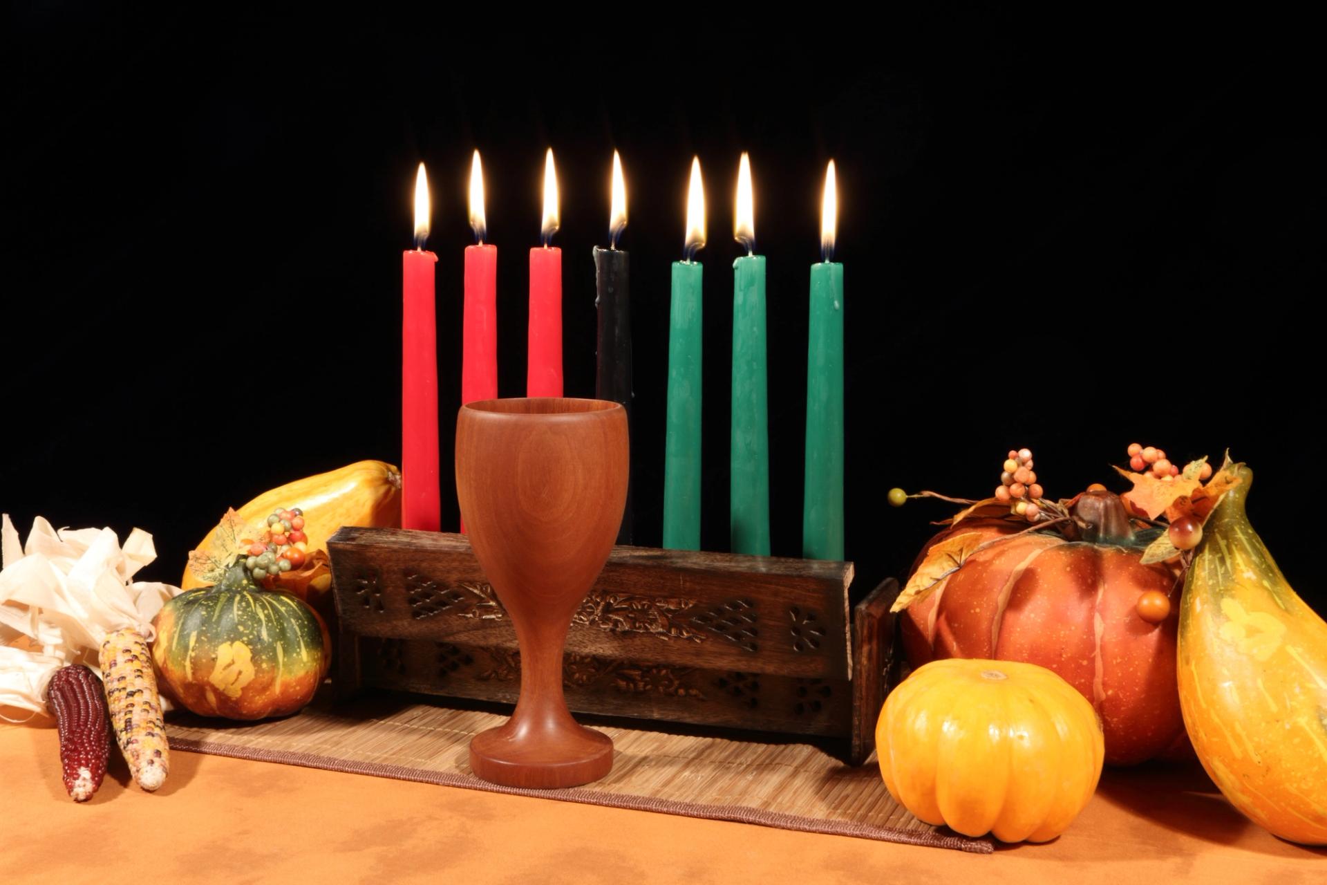 Kwanza candles on a table with fruit and glassware.