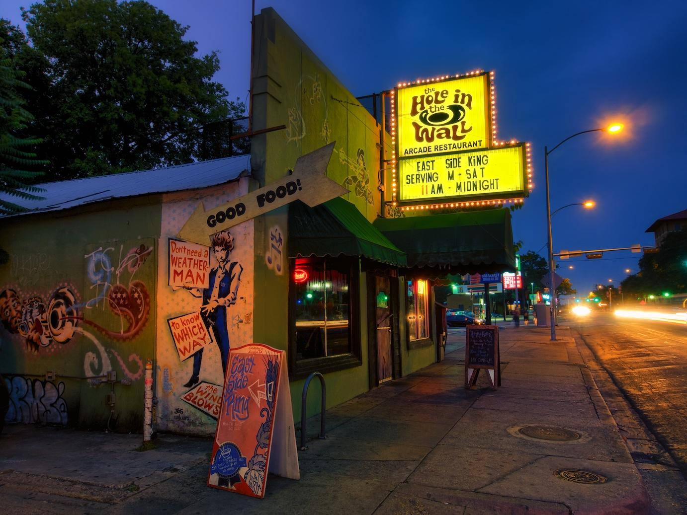 The outside of Hole in the Wall. The bar has a bright yellow sign with its name.