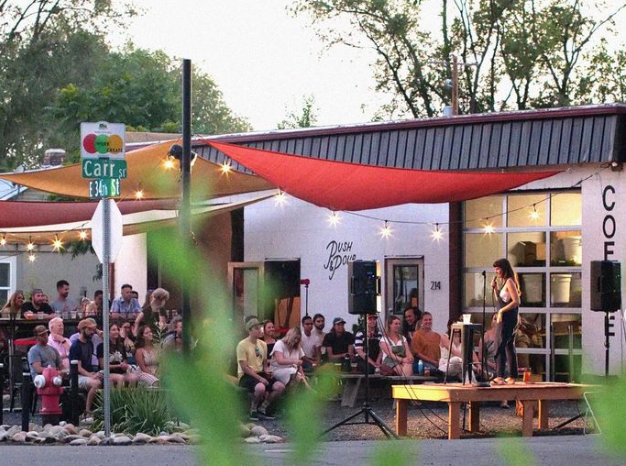 A photo of the Push & Pour patio showing a crowd of people watching a comedian on stage from across the intersection.