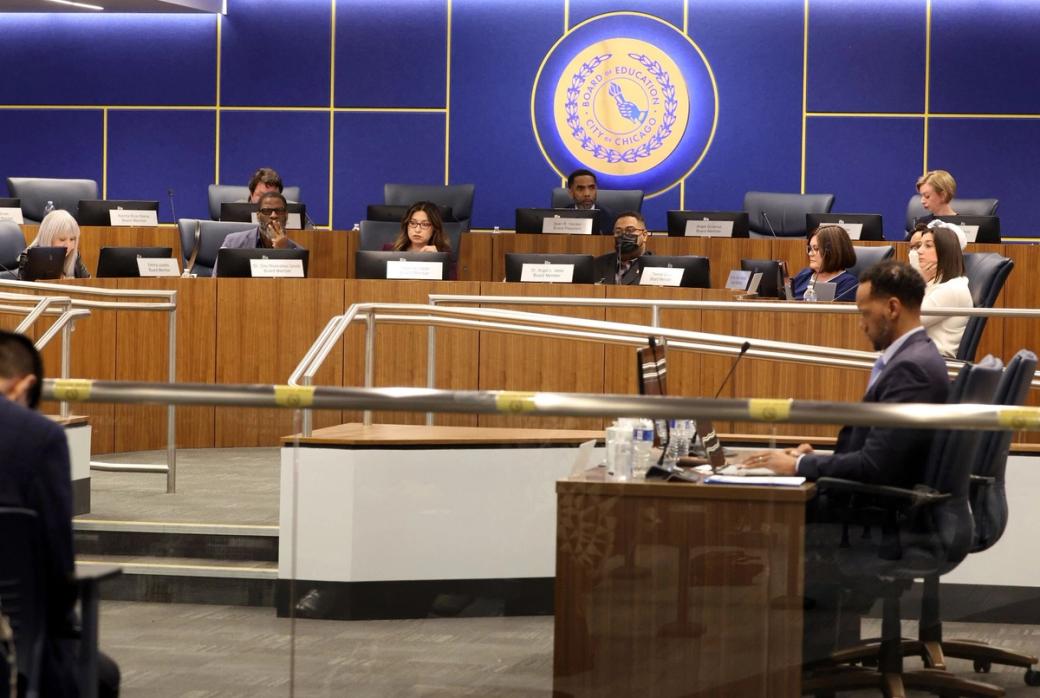 A meeting of the Chicago Board of Education, with board members seated at desks in a chamber beneath the Board of Education seal.