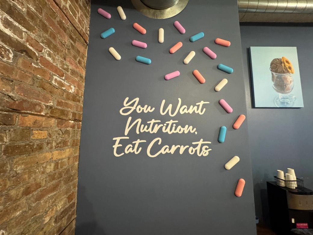 A sign on a chalkboard next to a brick wall.