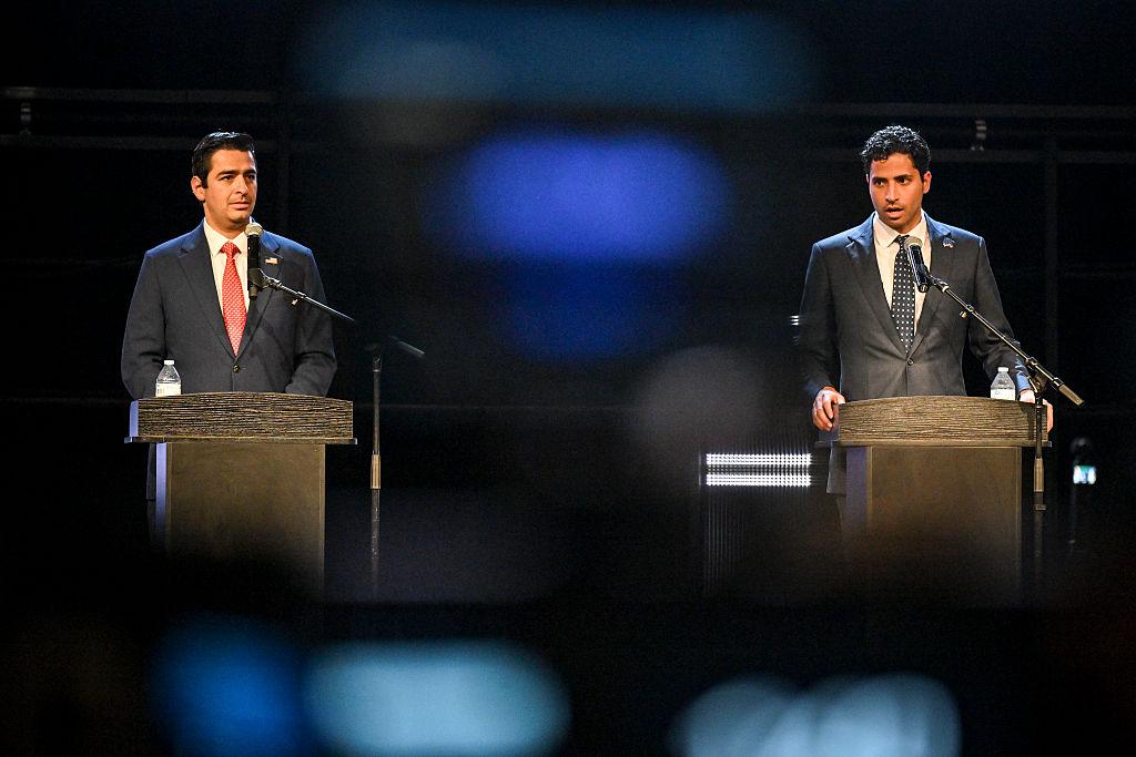 Gabe Evans (left) and Manny Rutinel both stand behind podiums with microphones.