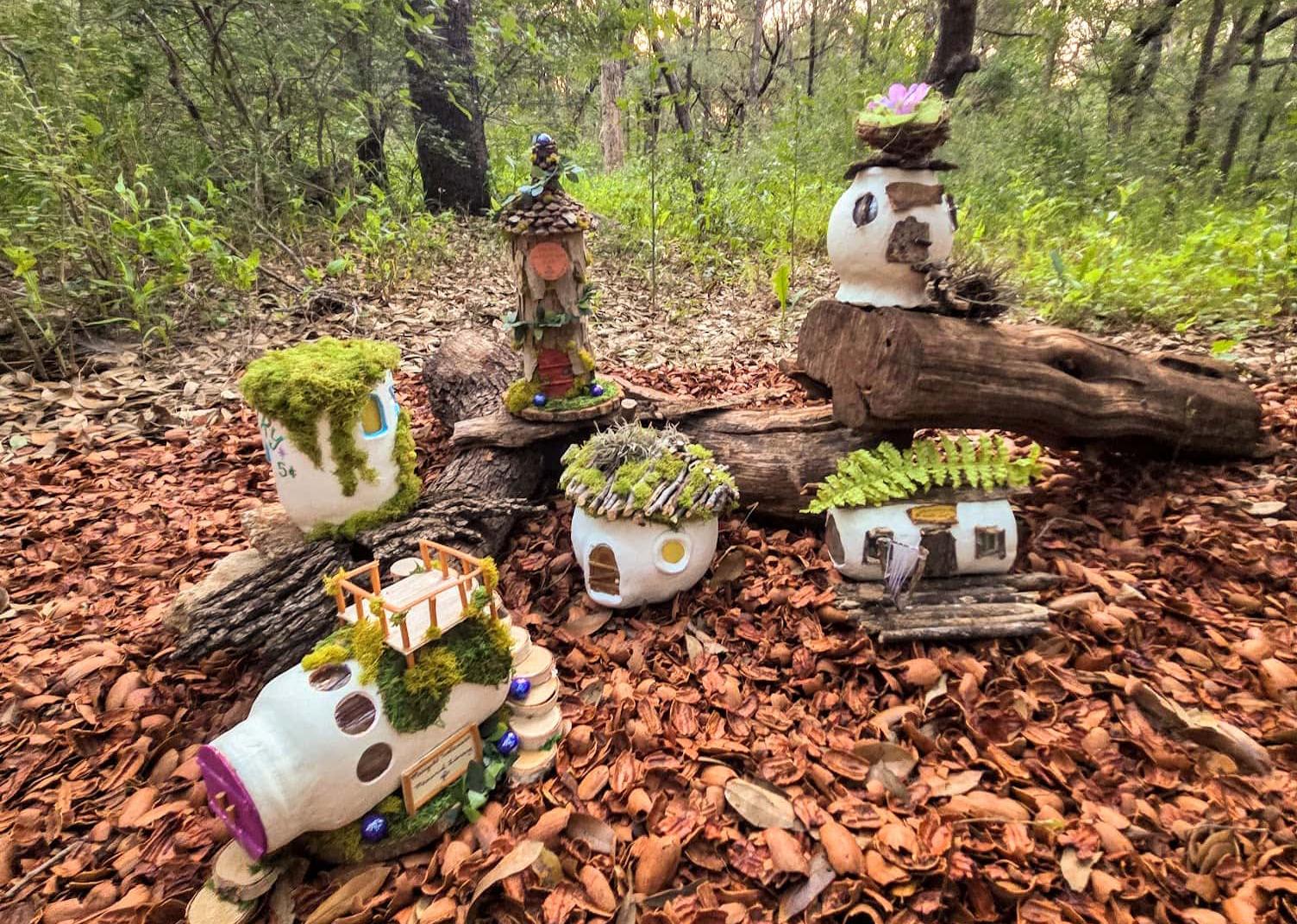 A small display of so-called fairy homes that are small and white. The homes are on logs.