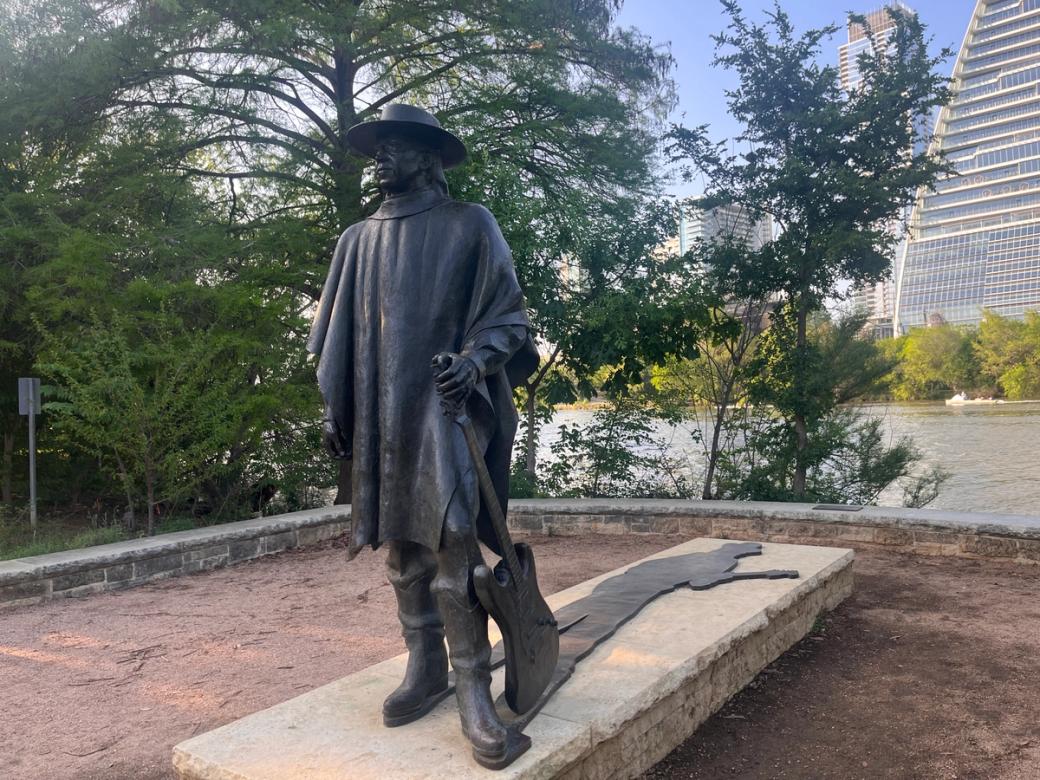 A statue of a man wearing a hat and holding a guitar.