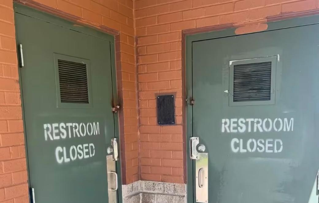 Green park bathroom doors spray painted with "Restroom Closed"