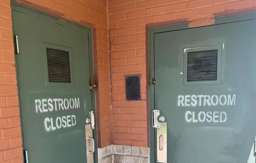 Green park bathroom doors spray painted with "Restroom Closed"