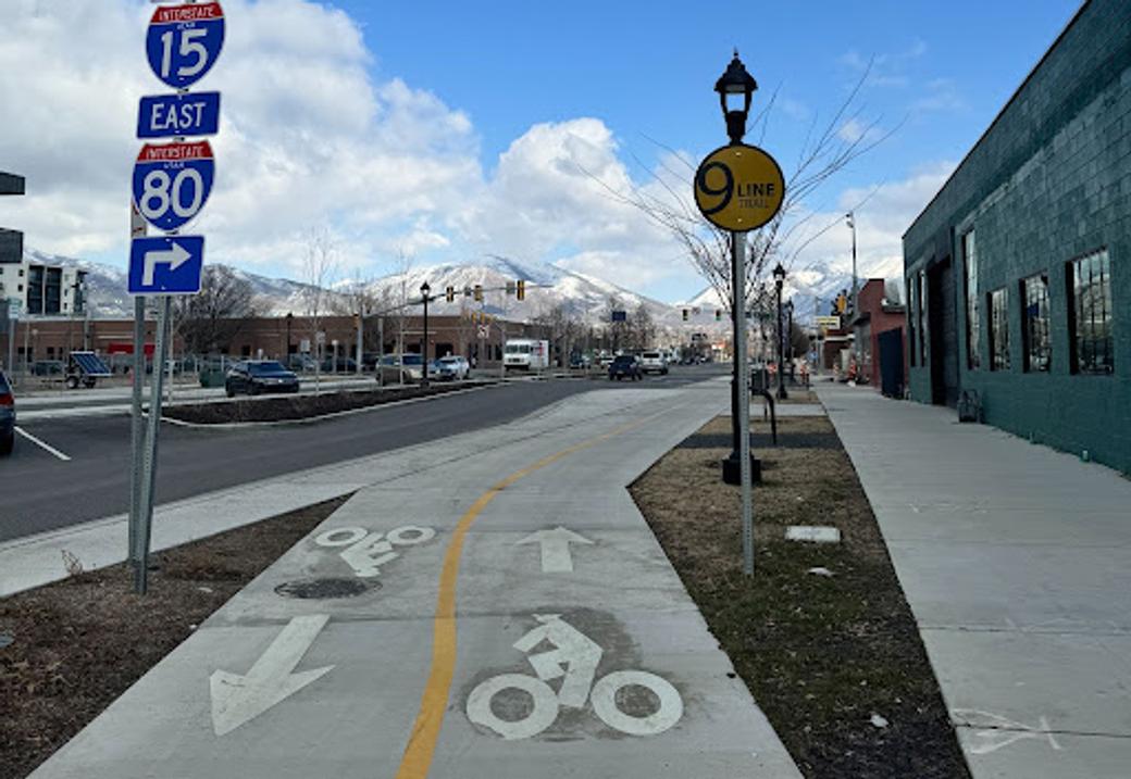 Shows the bike lane of the 9 Line Trail in Salt Lake City, with the Wasatch Mountains in the background.