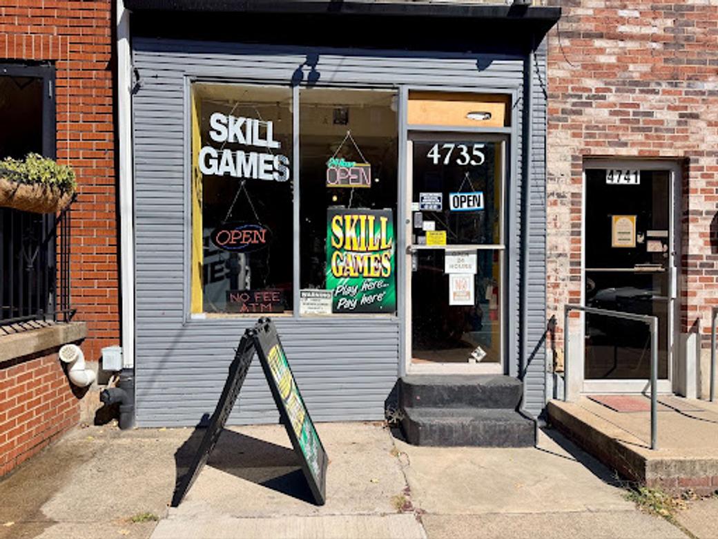Neon signs reading “SKILL GAMES” and “SMOKE SHOP” hang in the window of a convenience store that also advertises Pennsylvania lottery tickets.