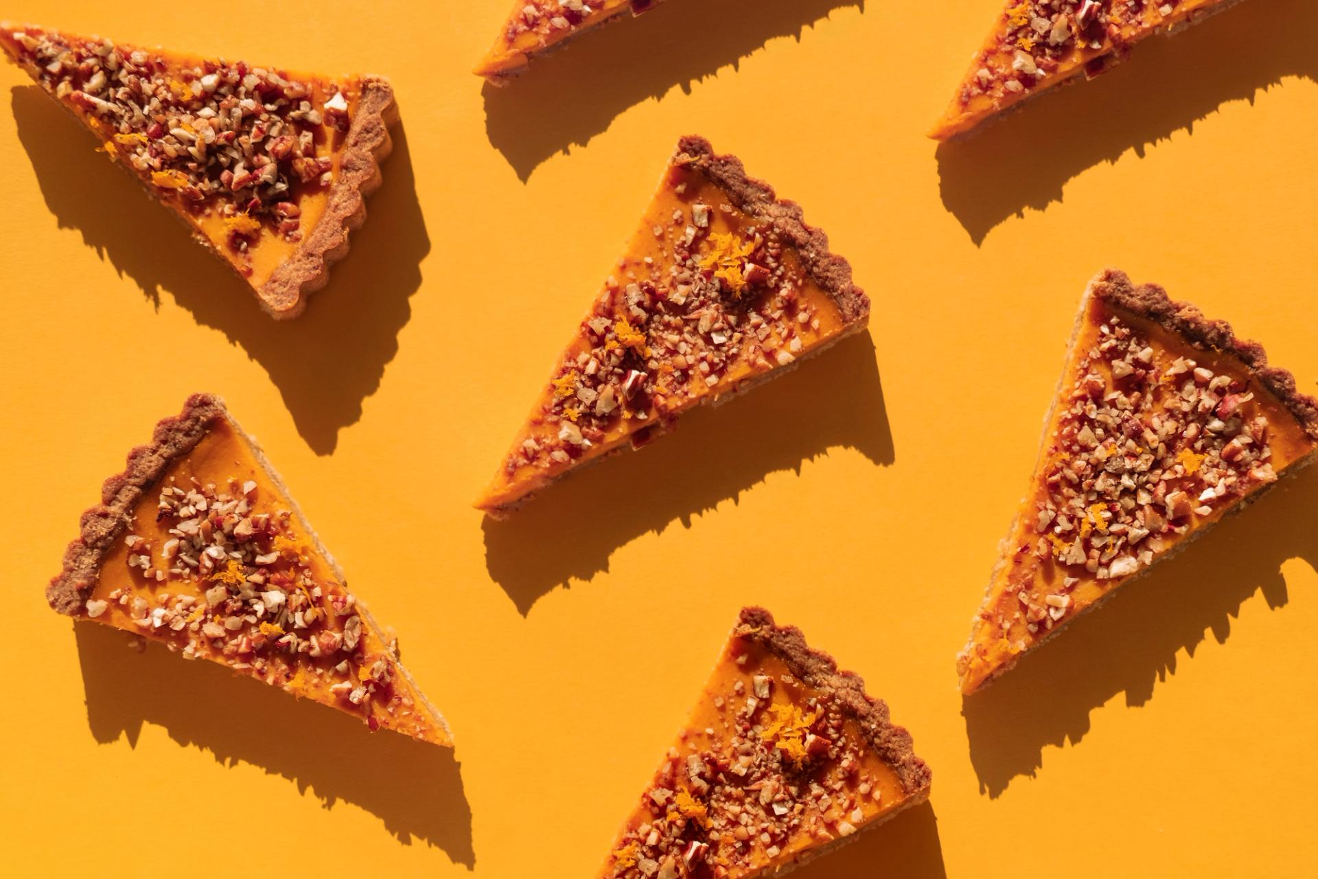 Slices of pumpkin pie against an orange background.