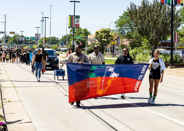 A group of people walk in the street holding flags.