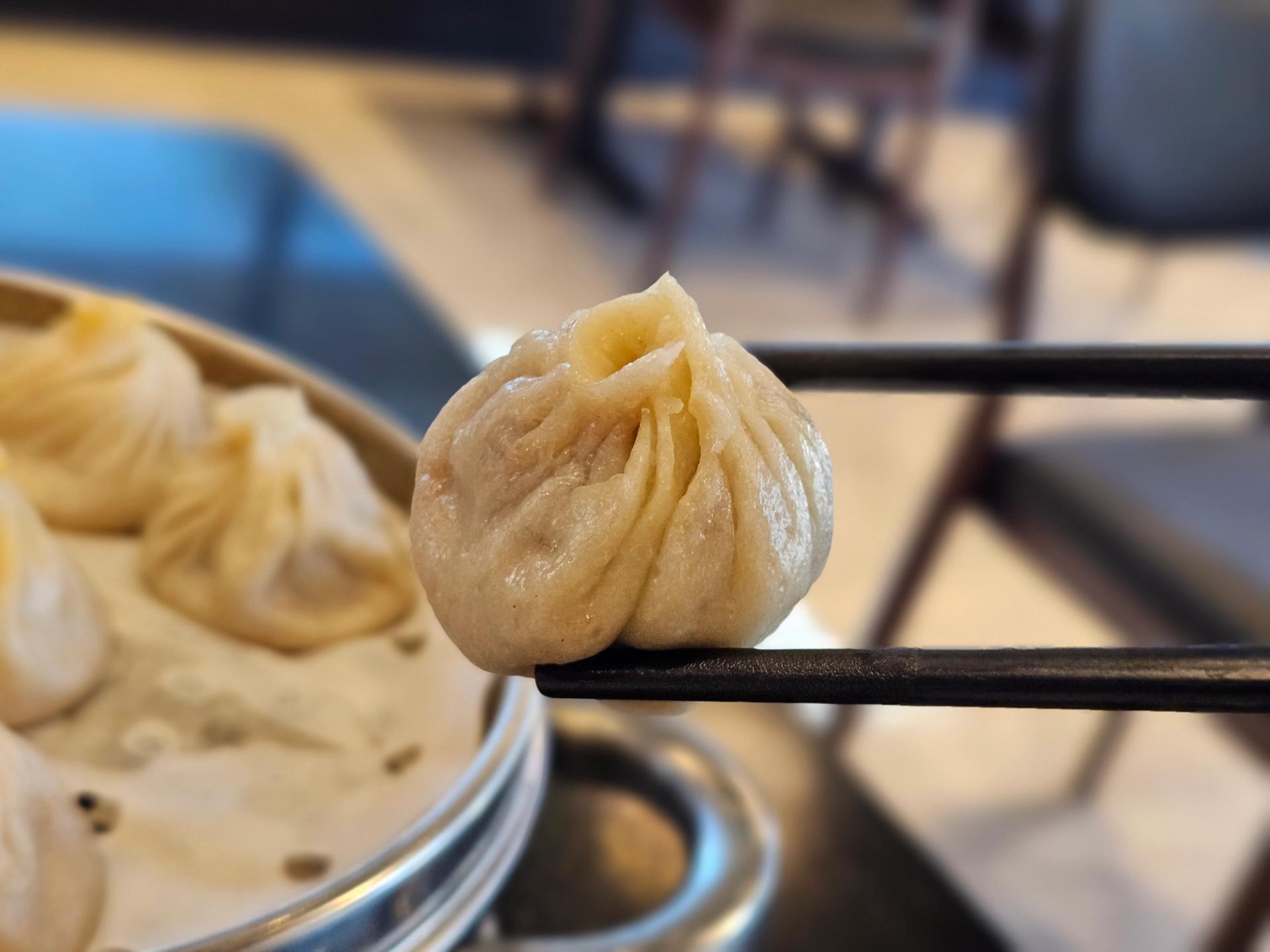 Chopsticks holding a soup dumpling.