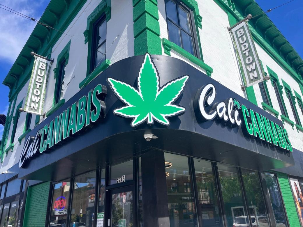 A storefront with a giant weed leaf sign and the words “Cali Cannabis.” The exterior has green accents. 