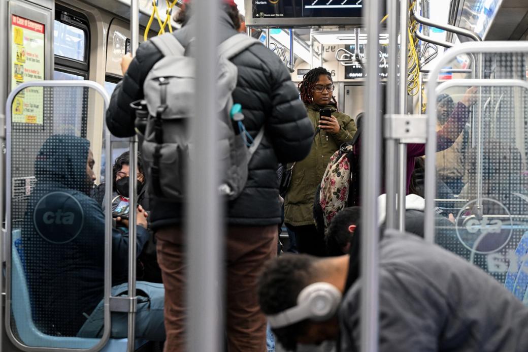 A group of people on a train. One of which is looking at her phone