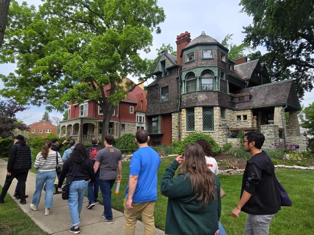 A group of people walking in front of an old looking house