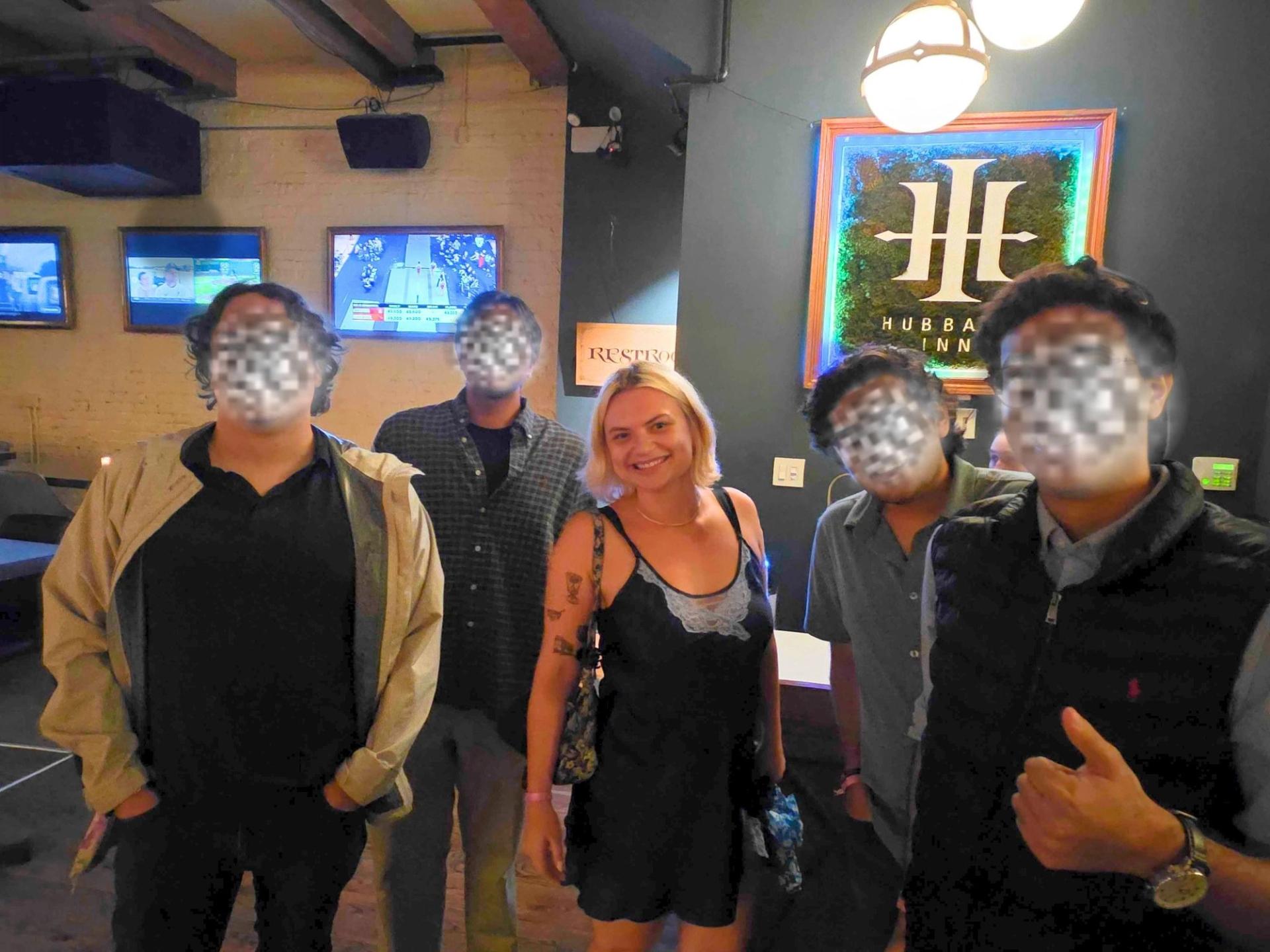 A woman smiling for the camera surrounded by men with their faces blurred