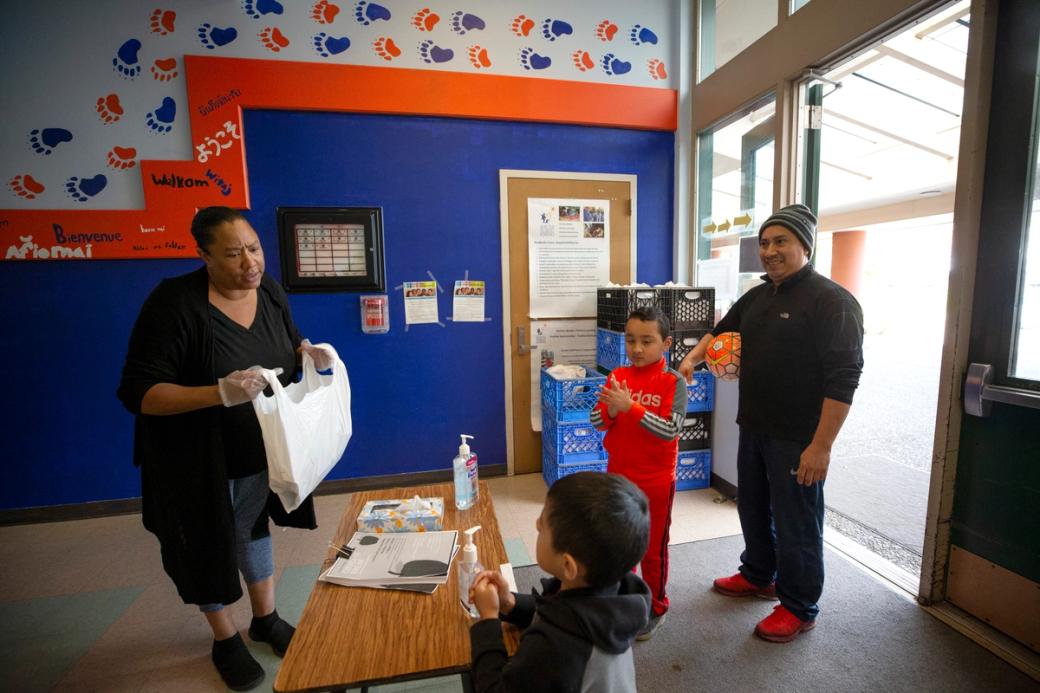 Cynthia Wright asks Carlos Jimenez, 4, what he would like in his lunch bag along with his brother Gio Jimenez, 6, and father, Arturo Jimenez, at Bailey Gatzert Elementary School