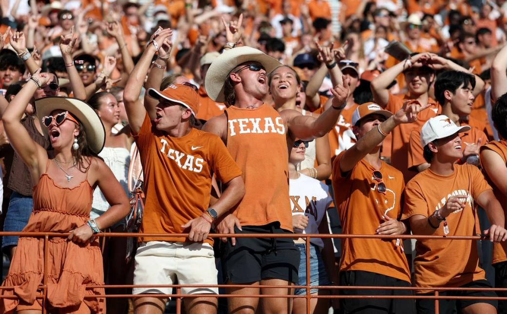 Texas football fans wearing burnt orange clothing cheer during a game
