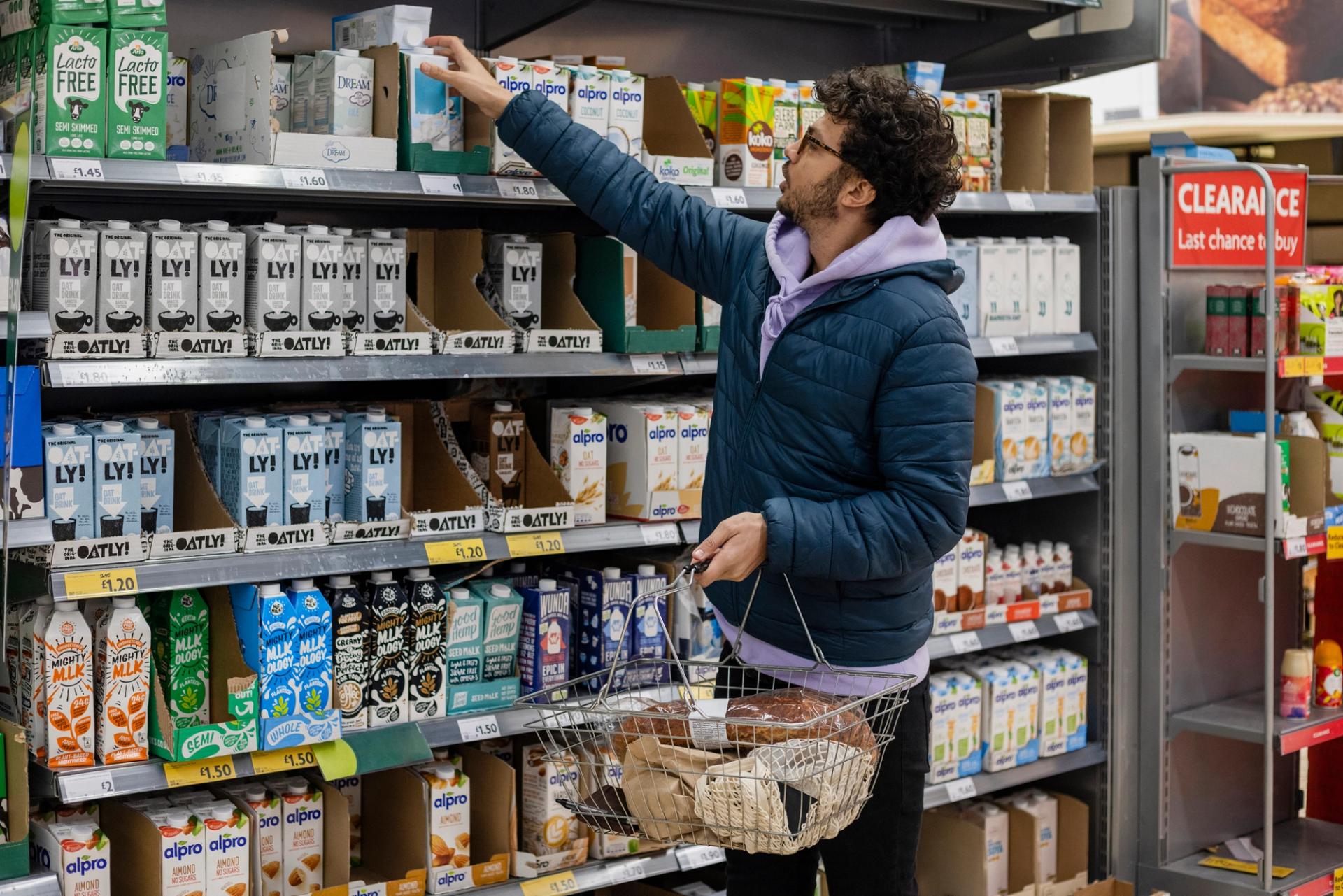 Man shopping for vegan milk option at grocery store cooler