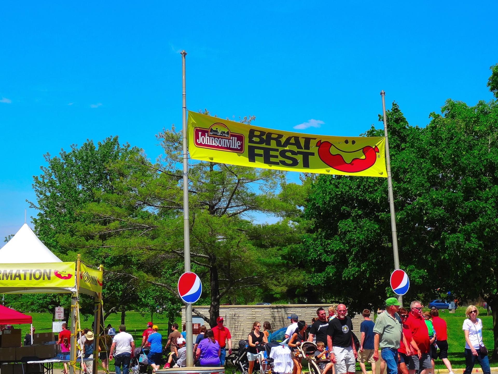 People walk under a large yellow banner in a park.