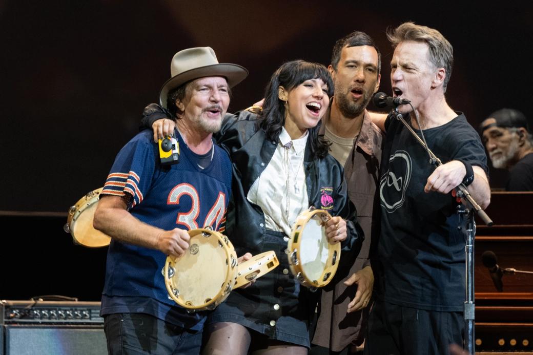 Four people with tambourines singing on stage