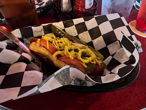 A hot dog with mustard sits in a basket with a black and white checkered lining