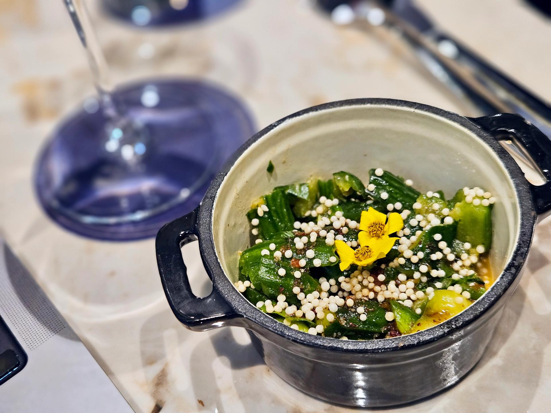 A cucumber salad next to a glass of wine.