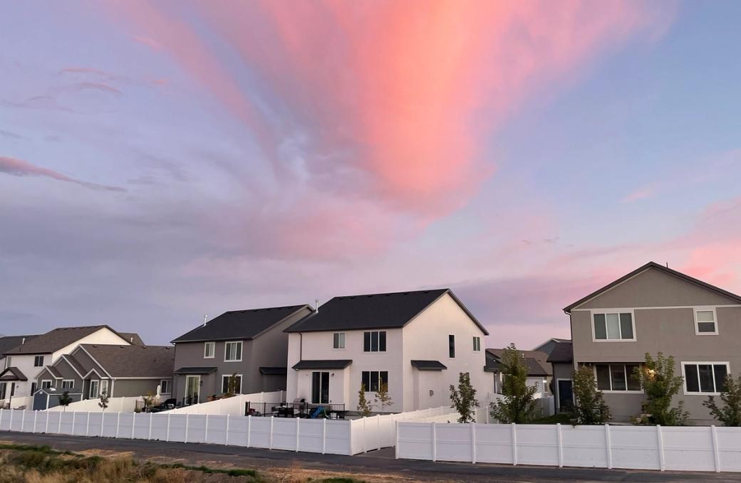 Houses in a neighborhood with pink clouds and a blue sky above.