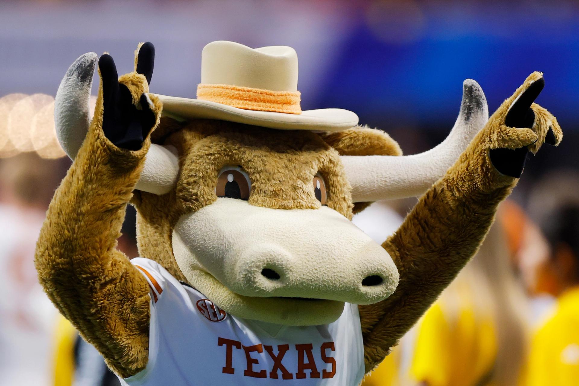 Bevo, the University of Texas at Austin's mascot, wears a brown cowboy hat and throws up two "hook 'em" signs.