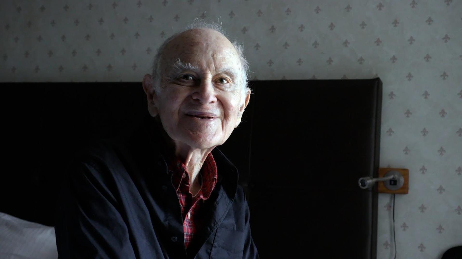 An older man sitting on a bed