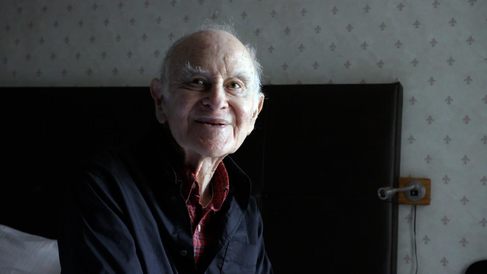 An older man sitting on a bed