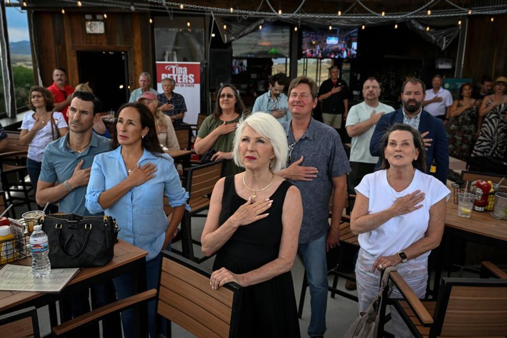 Tina Peters and supporters stand for the national anthem during a watch party for Peters’ 2019 secretary of state election race on Tuesday, June 28, 2022.