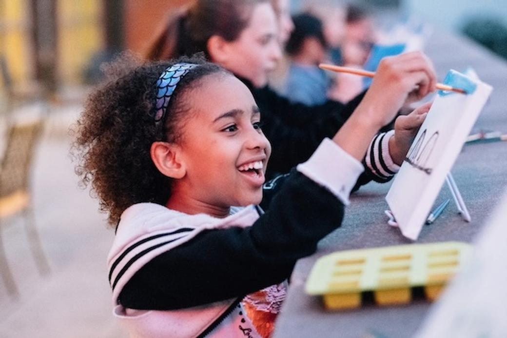 Image of girl painting a canvas at a table