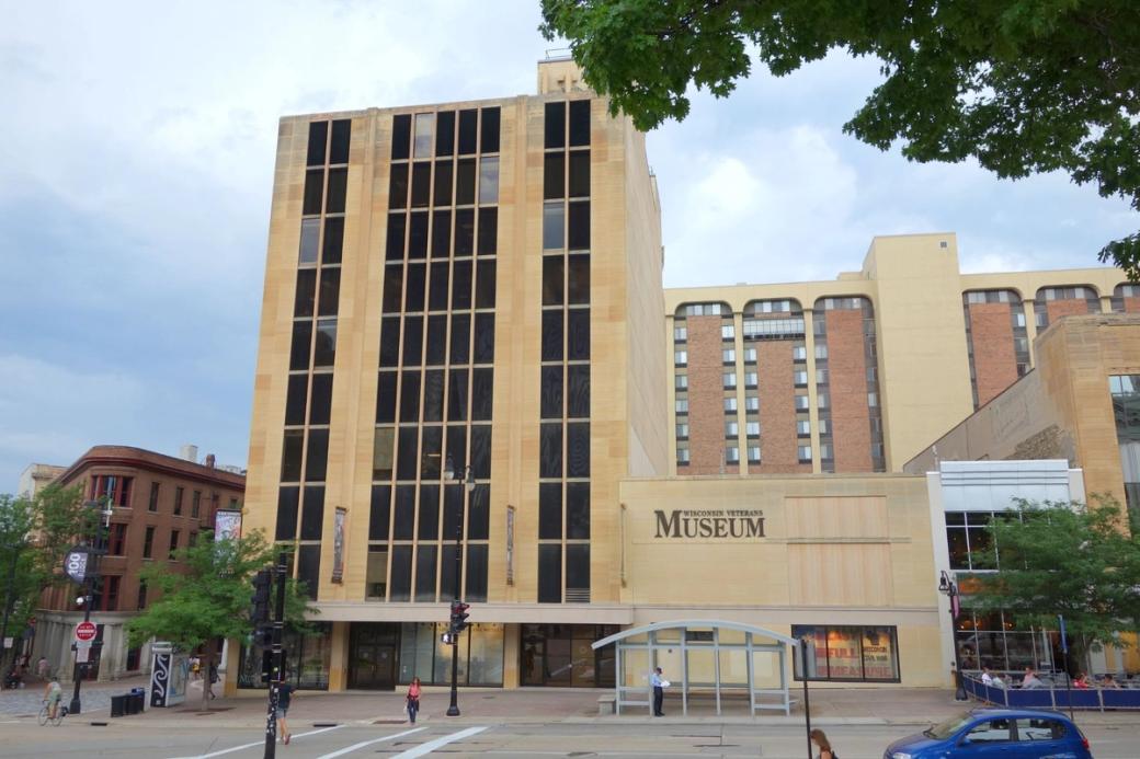 The Wisconsin Veterans Museum, a multi-story beige building with parking in front.