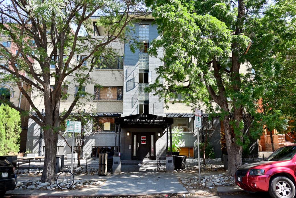 Street view of an apartment building with cars parked in front.