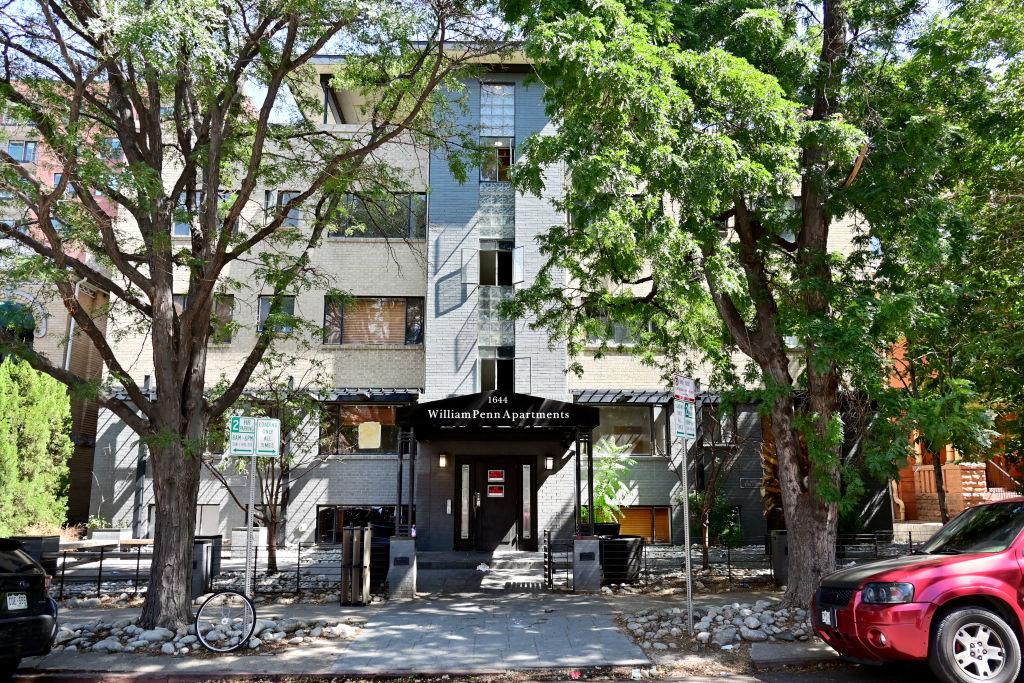 Street view of an apartment building with cars parked in front.