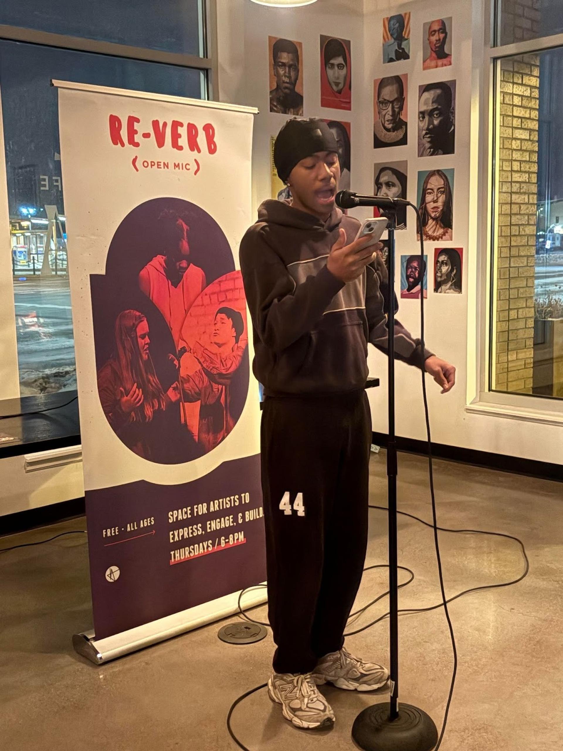 A person at a microphone reading off of their phone