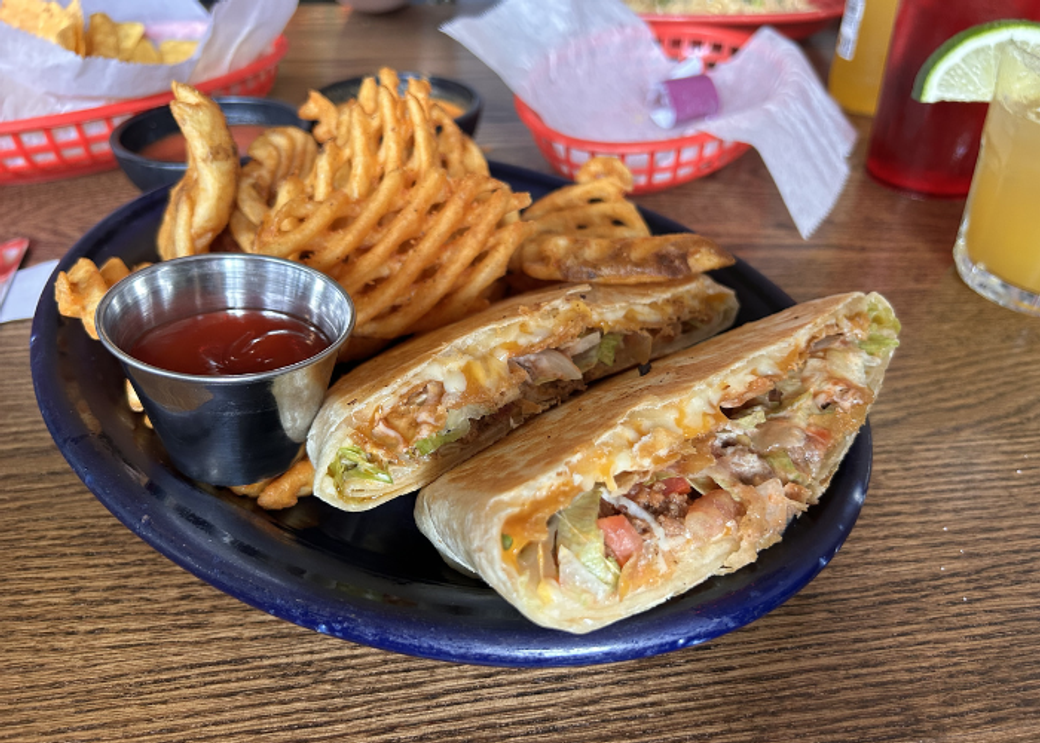 A plate with tacos and waffle fries.