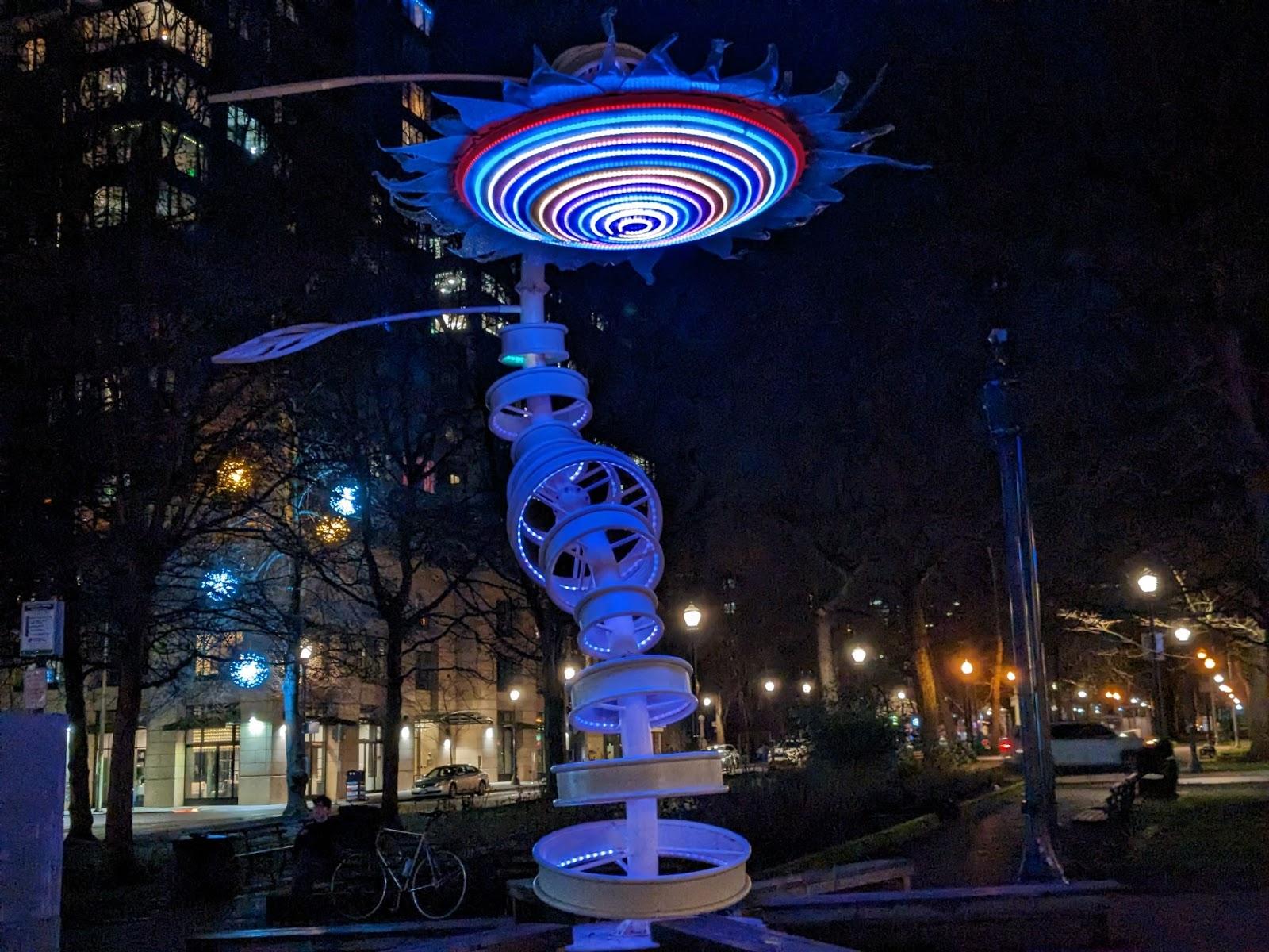 a sunflower shaped sculpture lit up red blue and white
