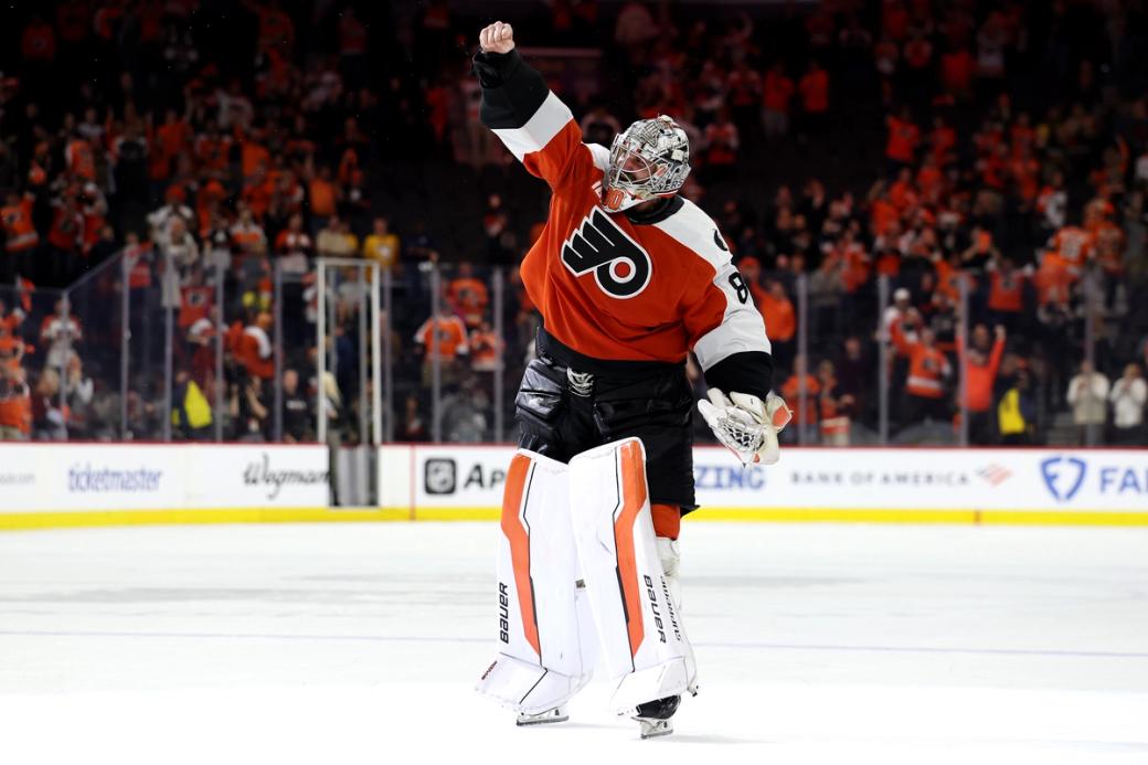 Flyers goaltender Dan Vladar raises a fist in the air in the middle of the rink