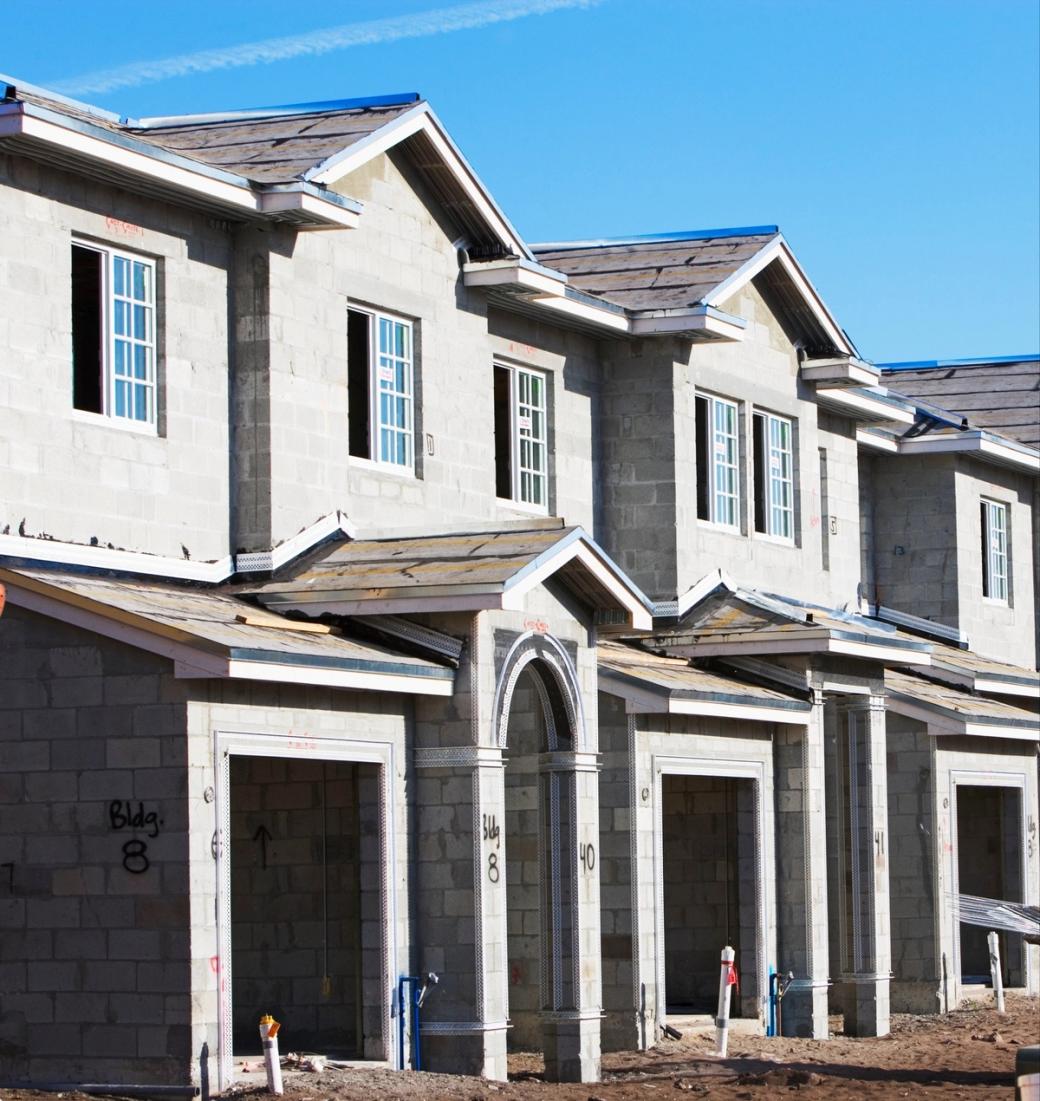  A gray and white multi-unit housing development with a repeating layout is under construction.