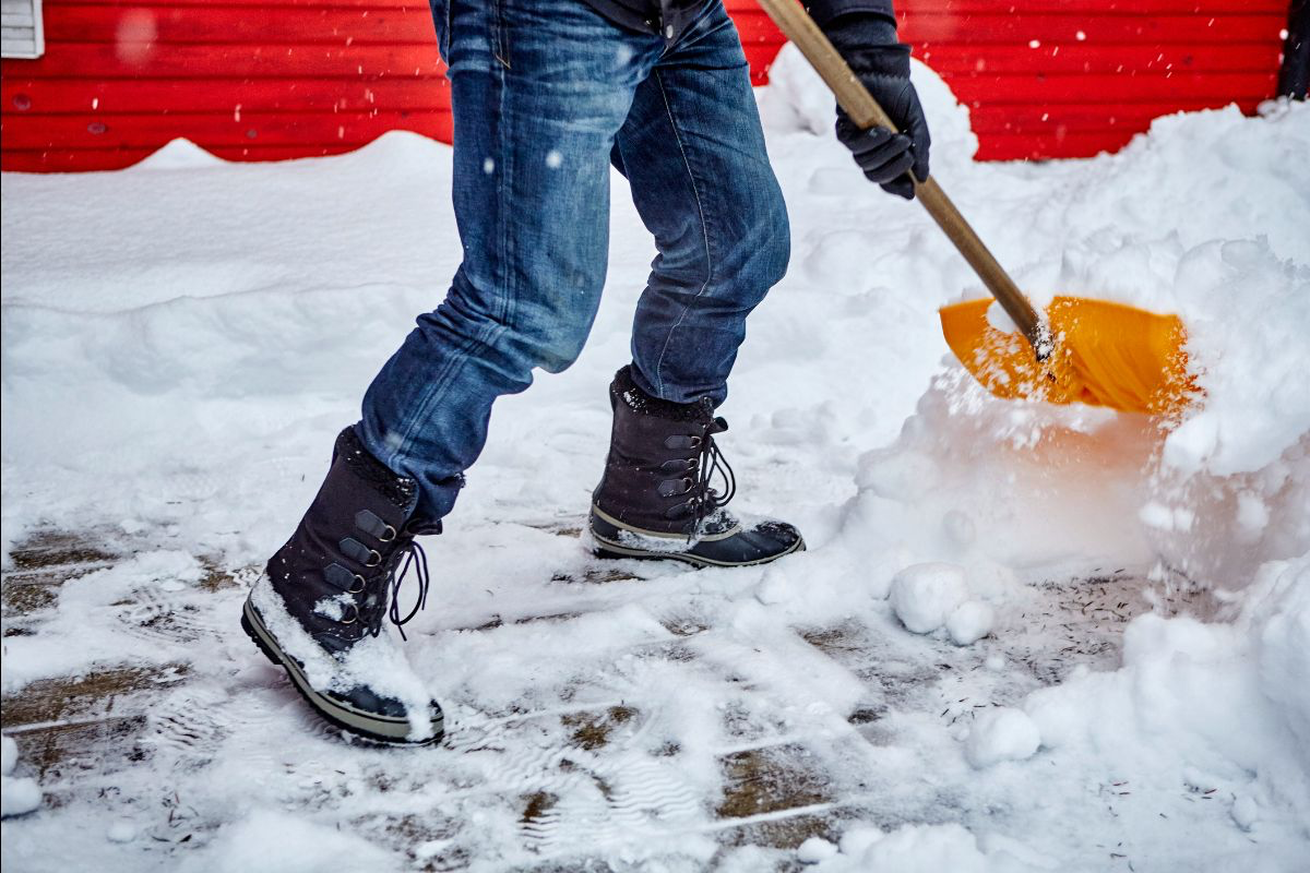 A snowy sidewalk being shoveled