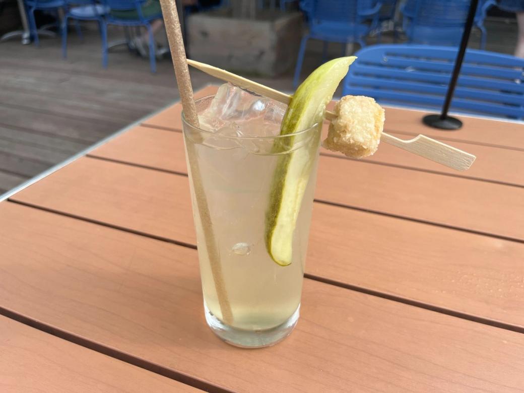 Beverage in glass with pickle in it sitting on patio table