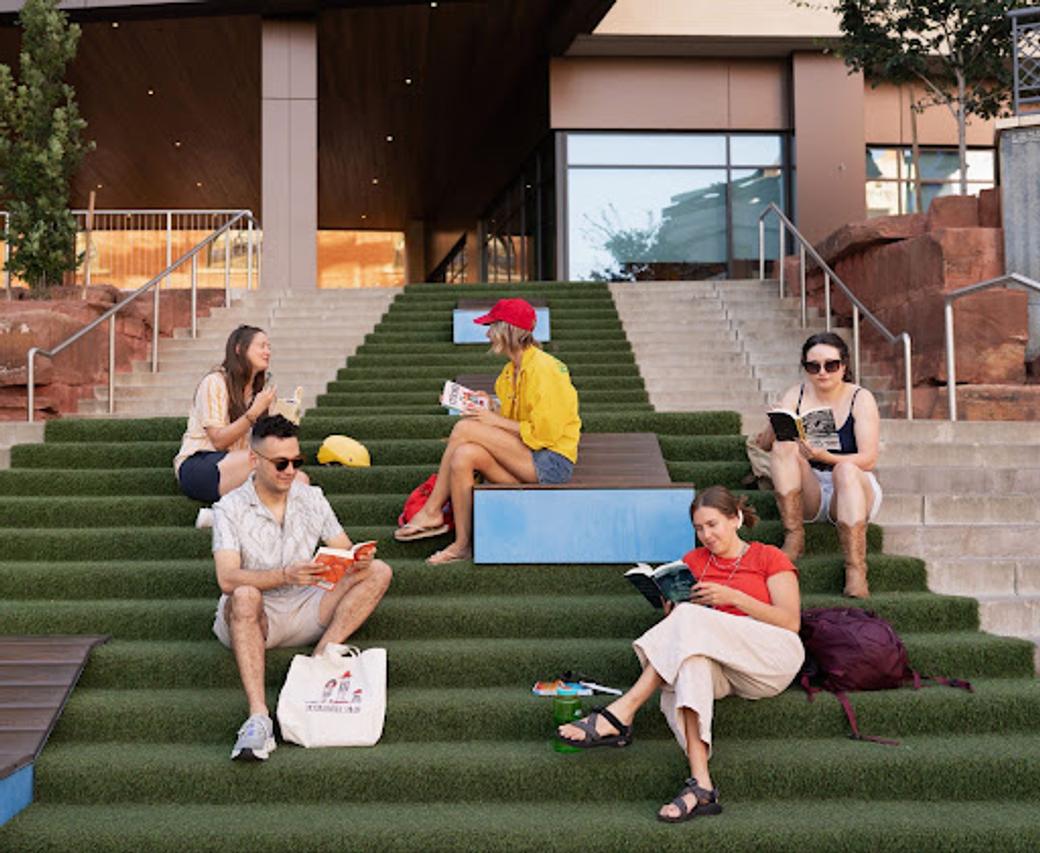 People reading books on grassy stairs at The Gateway in Salt Lake City. 