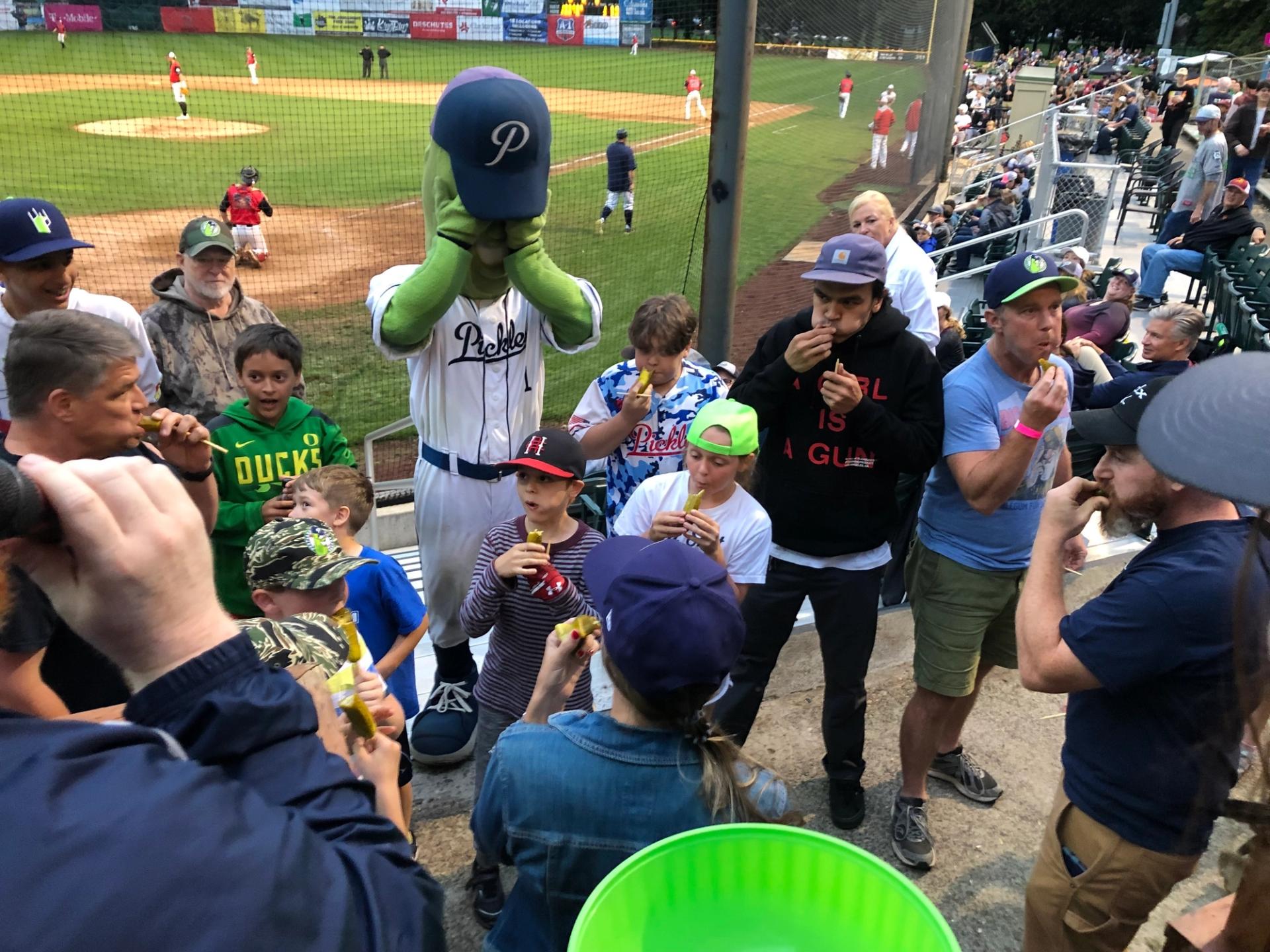 A pickles game at Walker Stadium where Dillon the pickle mascot is watching a pickle eating contest.