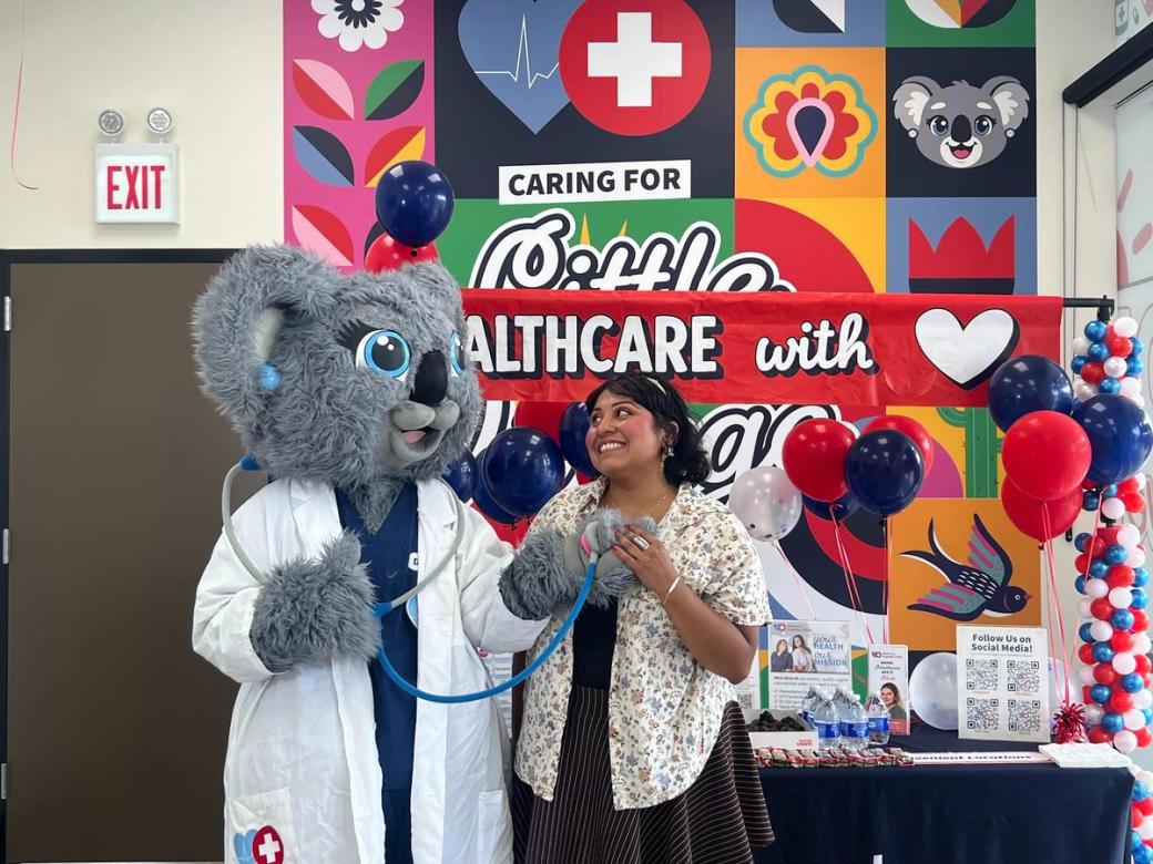 A woman standing next to someone in Koala costume wearing a doctors outfit
