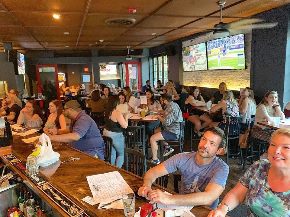 A group of people play trivia in a crowded bar