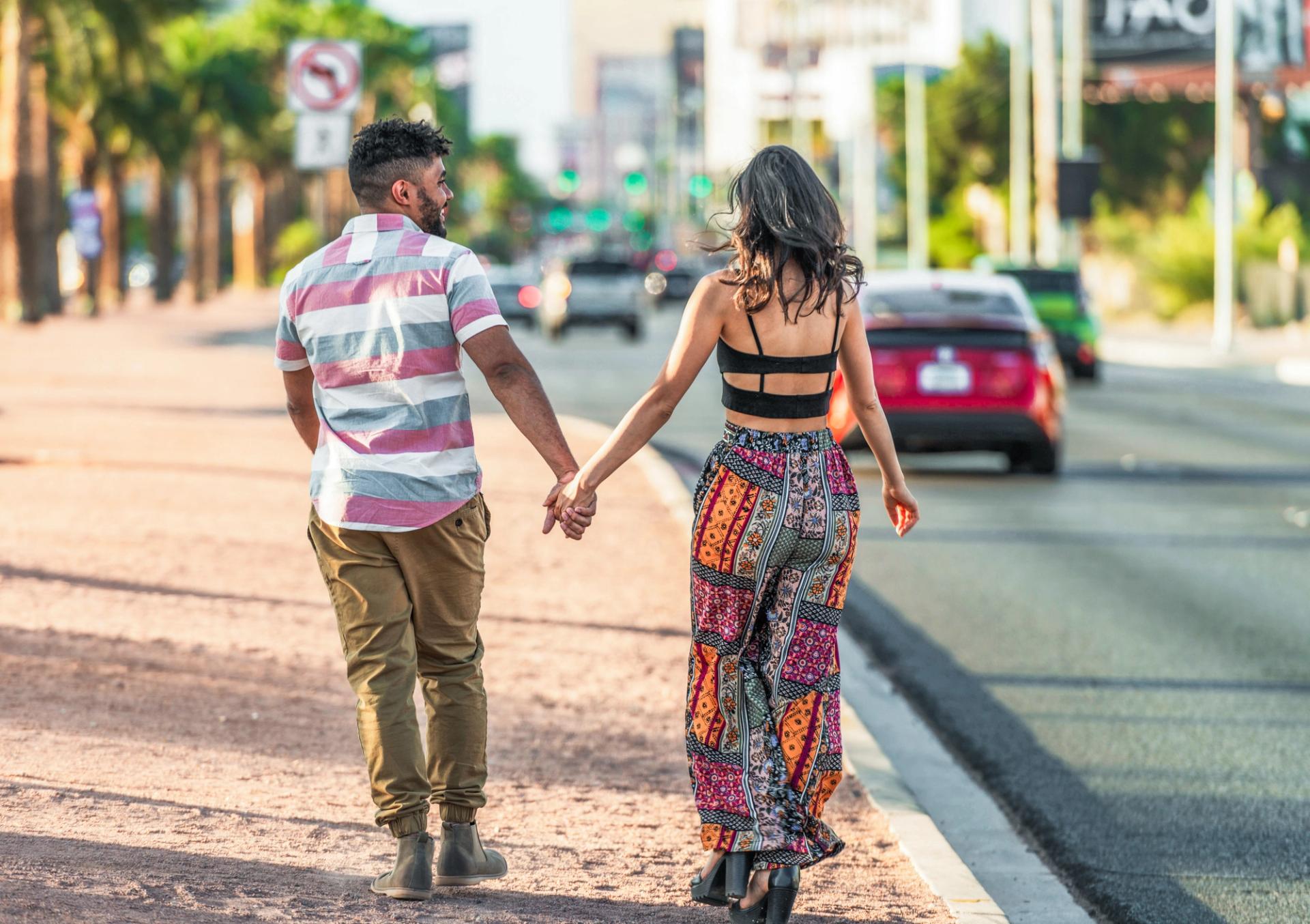 A couple holds hands while walking down the Vegas Strip.