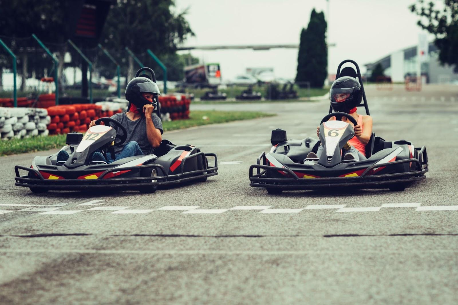 two people in go-karts wait at the startling line of a go-kart track